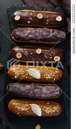 Sweet chocolate eclairs on black wooden board Sweet chocolate eclairs on black wooden board 101021022