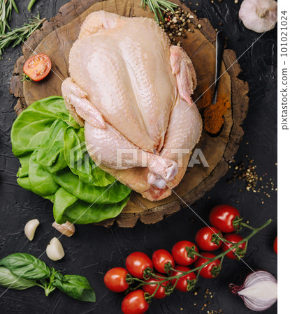 Whole raw chicken on a wooden board with spices for cooking, top view 101021024
