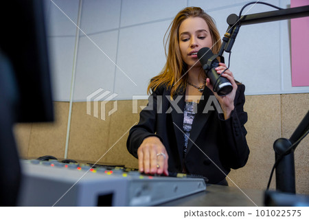 Cute blonde girl with microphone at the radio studio 101022575