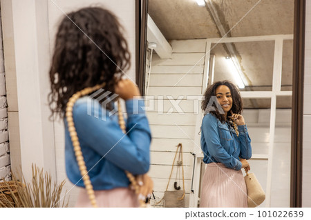 Cute young woman dressed in boho style posing near the mirror 101022639