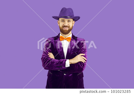 Studio portrait of happy bearded man in purple hat, velvet suit and orange bow tie 101023285