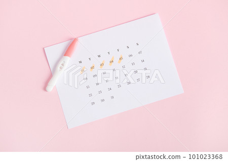 Rapid diagnosis of pregnancy at home. Top view of inkjet pregnancy test kits with biochemical reaction between hCG and urine appearing in two bars on white calendar with last menstruation dates marked Rapid diagnosis of pregnancy at home. Top view of inkjet pregnancy test kits with biochemical reaction between hCG and urine appearing in two bars on white calendar with last menstruation dates marked 101023368
