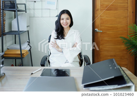 Portrait of a woman business owner showing a happy smiling face as he has successfully invested her business using computers and financial budget documents at work. 101023460