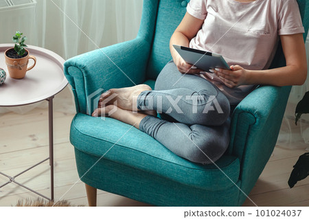 Young woman using tablet while sitting in a comfortable chair 101024037