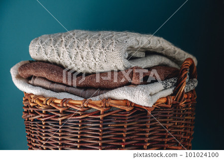 Stack of knitted sweaters on wicker basket. 101024100