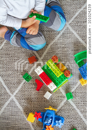 Child playing with toy blocks sitting on floor 101024239