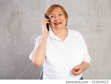 Older woman talking over phone proudly with happy confident grin 101024417