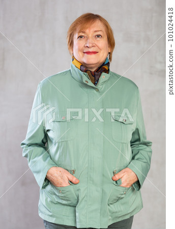 Senior woman standing confidently dressed in warm clothes with smile full of cheer 101024418