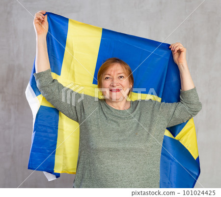 Smiling elderly woman holding national flag of Sweden Smiling elderly woman holding national flag of Sweden 101024425