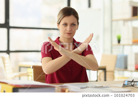 Woman manager shows Stop gesture at desk in company office Woman manager shows Stop gesture at desk in company office 101024703