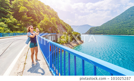 Young woman walking on the bridge across Piva lake in Montenegro 101025287