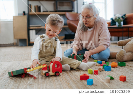 Grandmother playing with her little grandson,building a block set. Grandmother playing with her little grandson,building a block set. 101025299