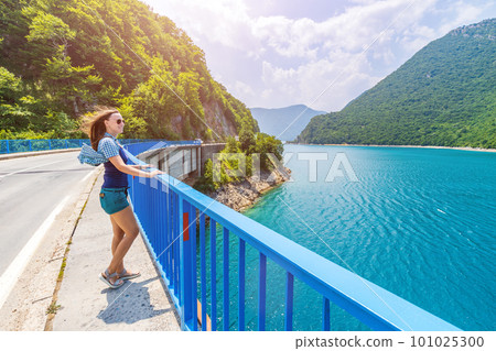 Young woman walking on the bridge across Piva lake in Montenegro 101025300