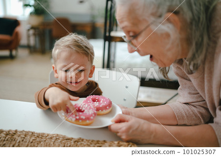 Little boy having snack with his grandmother. 101025307