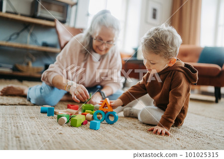 Grandmother playing with her little grandson,building a block set. Grandmother playing with her little grandson,building a block set. 101025315