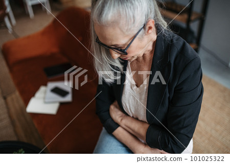 High angle view of senior woman with stomach ache. 101025322