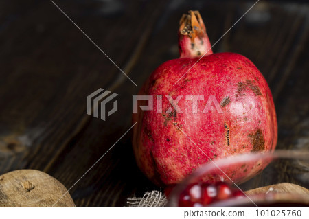 A small ripe red pomegranate is lying on the table A small ripe red pomegranate is lying on the table 101025760