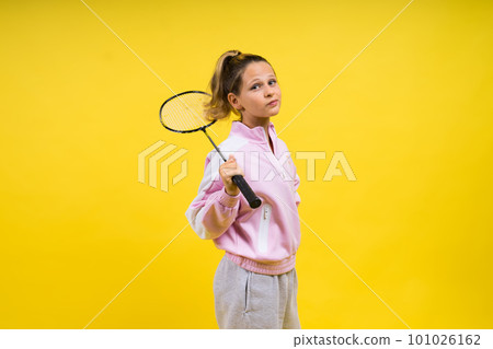 Full length studio photo of ten year old girl holding badminton racket and isolated on yellow. Full length studio photo of ten year old girl holding badminton racket and isolated on yellow. 101026162