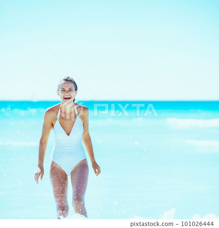 Happy young woman playing with waves on beach 101026444