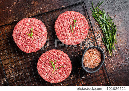 Raw burger cutlet from beef meat with spices and rosemary ready for cooking. Dark background. Top view 101026521
