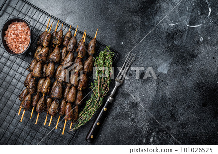 Grilled shish kebab with chicken hearts on a grill. Black background. Top view. Copy space 101026525