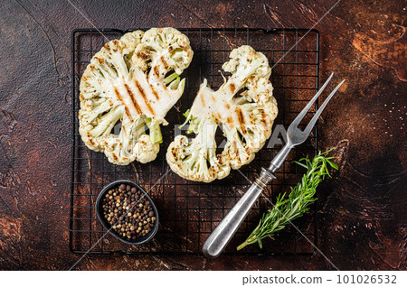 Grilled cauliflower steak with rosemary and spices, Vegan cuisine. Dark background. Top view Grilled cauliflower steak with rosemary and spices, Vegan cuisine. Dark background. Top view 101026532