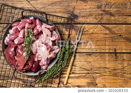 Raw bird giblets meat set, chicken offals, liver, hearts, gizzards Stomach. Wooden background. Top view. Copy space Raw bird giblets meat set, chicken offals, liver, hearts, gizzards Stomach. Wooden background. Top view. Copy space 101026533