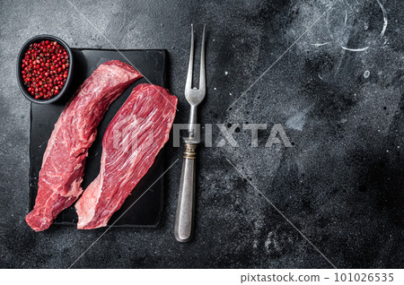 Bavette raw beef meat steak or Sirloin flap on marble board. Black background. Top view. Copy space Bavette raw beef meat steak or Sirloin flap on marble board. Black background. Top view. Copy space 101026535