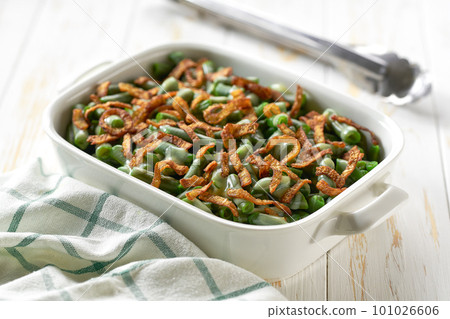 green bean casserole with crispy fried shallots onions on a white wooden table. 101026606
