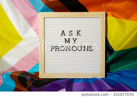 ASK MY PRONOUNS text Neo pronouns concept on Rainbow flag background gender pronouns. Non-binary people rights transgenders. Lgbtq community support assume my gender tolerance equal rights ASK MY PRONOUNS text Neo pronouns concept on Rainbow flag background gender pronouns. Non-binary people rights transgenders. Lgbtq community support assume my gender tolerance equal rights 101027050