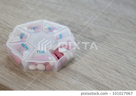Organizer weekly shots Closeup of medical pill box with doses of tablets for daily take medicine with white pink drugs and capsules. Daily vitamins at home. Health care and diseases cure 101027067