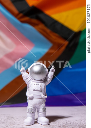 Toy astronaut on Rainbow LGBTQIA flag made from silk material background. Happy pride month. Symbol of LGBTQ pride month. Equal rights. Peace and freedom. Support LGBTQIA community Toy astronaut on Rainbow LGBTQIA flag made from silk material background. Happy pride month. Symbol of LGBTQ pride month. Equal rights. Peace and freedom. Support LGBTQIA community 101027173