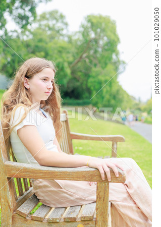 Profile of a foreign girl sitting on a park bench (vertical photo) Profile of a foreign girl sitting on a park bench (vertical photo) 101029050