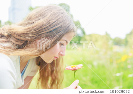 Profile of a girl who brings her face closer to a pink gerbera Profile of a girl who brings her face closer to a pink gerbera 101029052