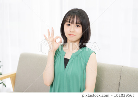 年輕女人坐在沙發上,做出 OK 的手勢 年輕女人坐在沙發上,做出 OK 的手勢 101029565