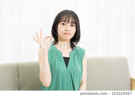 年輕女人坐在沙發上,做出 OK 的手勢 年輕女人坐在沙發上,做出 OK 的手勢 101029567