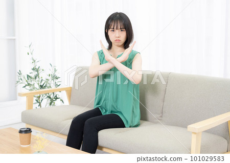 坐在沙發上做 NG 手勢的年輕女子 101029583