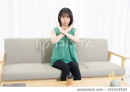 坐在沙發上做 NG 手勢的年輕女子 101029584