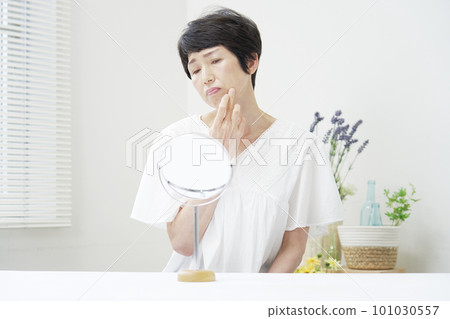 A middle-aged woman who is worried about looking at her face in the mirror A middle-aged woman who is worried about looking at her face in the mirror 101030557