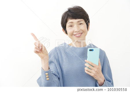 A middle-aged woman holding a smartphone and pointing to the left White background 101030558