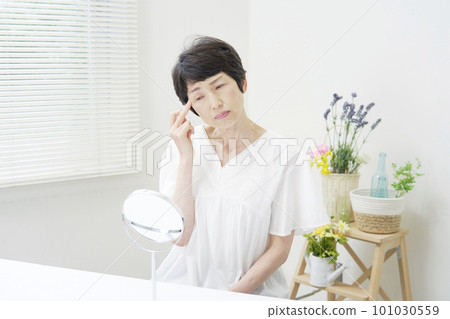 A middle-aged woman who is worried about looking at her face in the mirror A middle-aged woman who is worried about looking at her face in the mirror 101030559