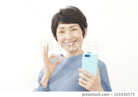 中年婦女拿著智能手機並簽署 OK 白色背景 101030573