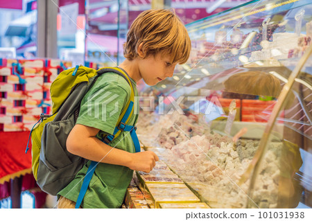 The boy looks at the counter with Turkish sweets. Traditional oriental sweet pastry cookies, nuts, dried fruits, pastilles, marmalade, Turkish desert with sugar, honey and pistachio, in display at a The boy looks at the counter with Turkish sweets. Traditional oriental sweet pastry cookies, nuts, dried fruits, pastilles, marmalade, Turkish desert with sugar, honey and pistachio, in display at a 101031938