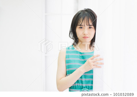 Young woman standing by the window and looking at you 101032089