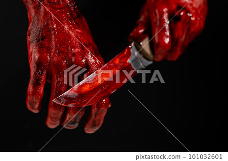 Man holding knife with bloody hand on black background.  101032601