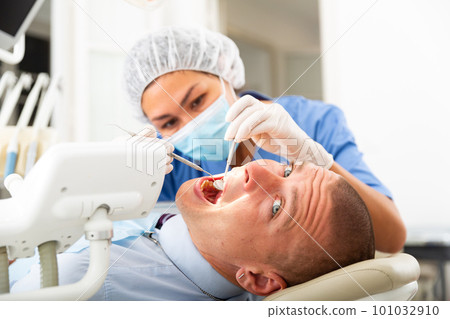 Dentist inspects male patient teeth 101032910