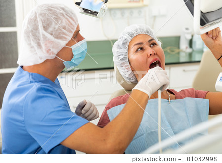 Qualified man dentist conducts an examination of a woman patient using an apexlocator Qualified man dentist conducts an examination of a woman patient using an apexlocator 101032998