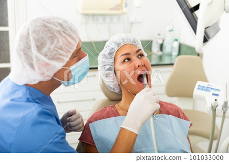 Dentist examining patient teeth with camera 101033000