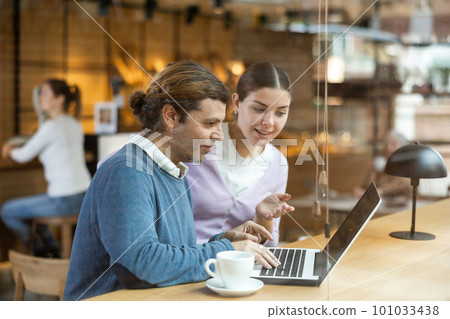 Calm caucasian man and woman sitting in cafe diligently doing their work on laptop Calm caucasian man and woman sitting in cafe diligently doing their work on laptop 101033438
