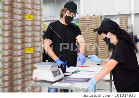 Manager in protective mask invites factory warehouse worker to sign documents 101034636